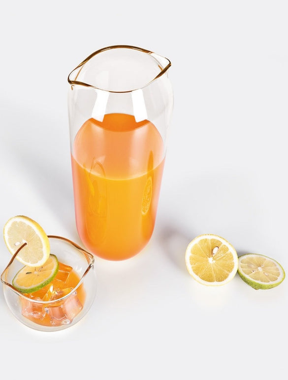 Caraffa e bicchiere con limoni tagliati